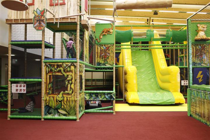 Großer Indoor-Kletterdschungel mit Rutschen, Kletterelementen und Spieltürmen für Kinder.