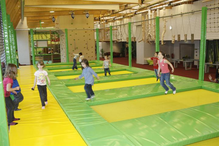 Kinder springen auf mehreren Indoor-Trampolinen im Trampolinbereich des Monki Parks.