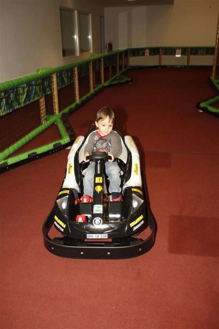 Kind fährt mit einem elektrischen Go-Kart auf der Indoor-Rennstrecke im Monki Park.
